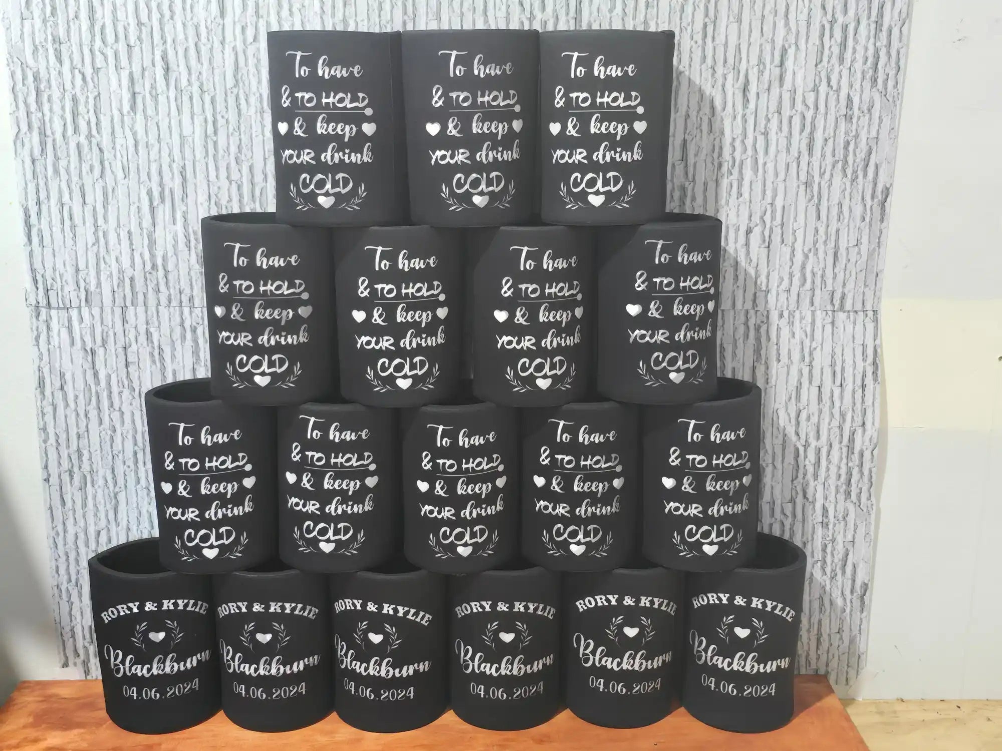 Collection of black cups or tumblers with white text and designs stacked in rows.