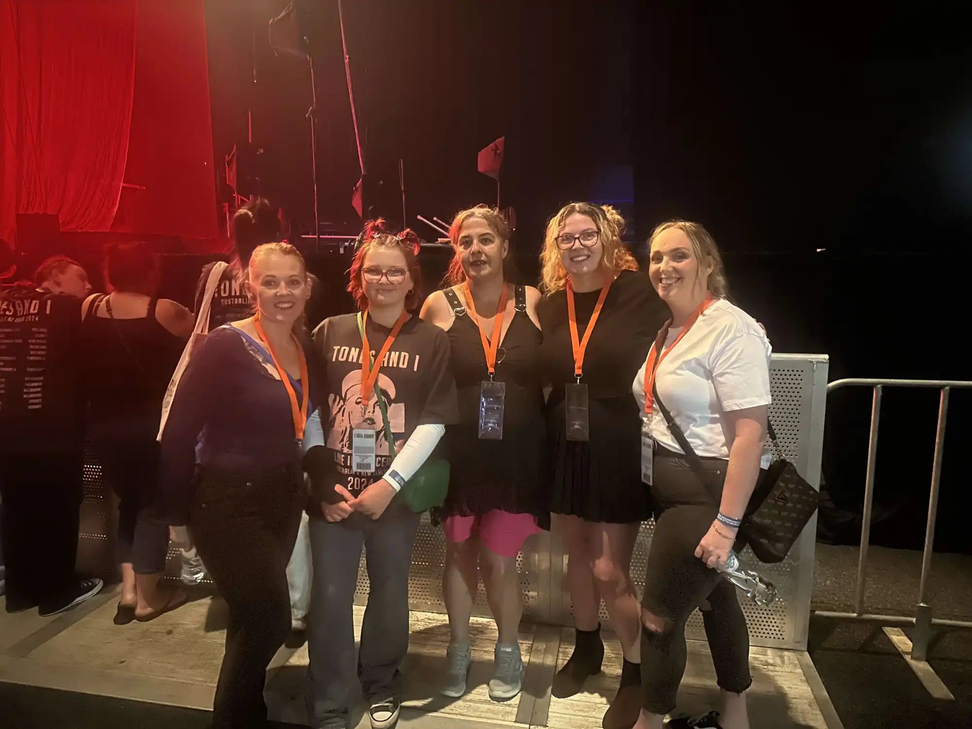 A group of people wearing lanyards posing together on what appears to be a stage area.